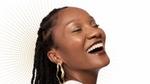 An image to promote Dove Regenerative dermocosmetics skincare products. A Black woman is shown in side profile, smiling. Background is white with gold dots.