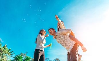 A young family blowing bubbles under a clear blue sky