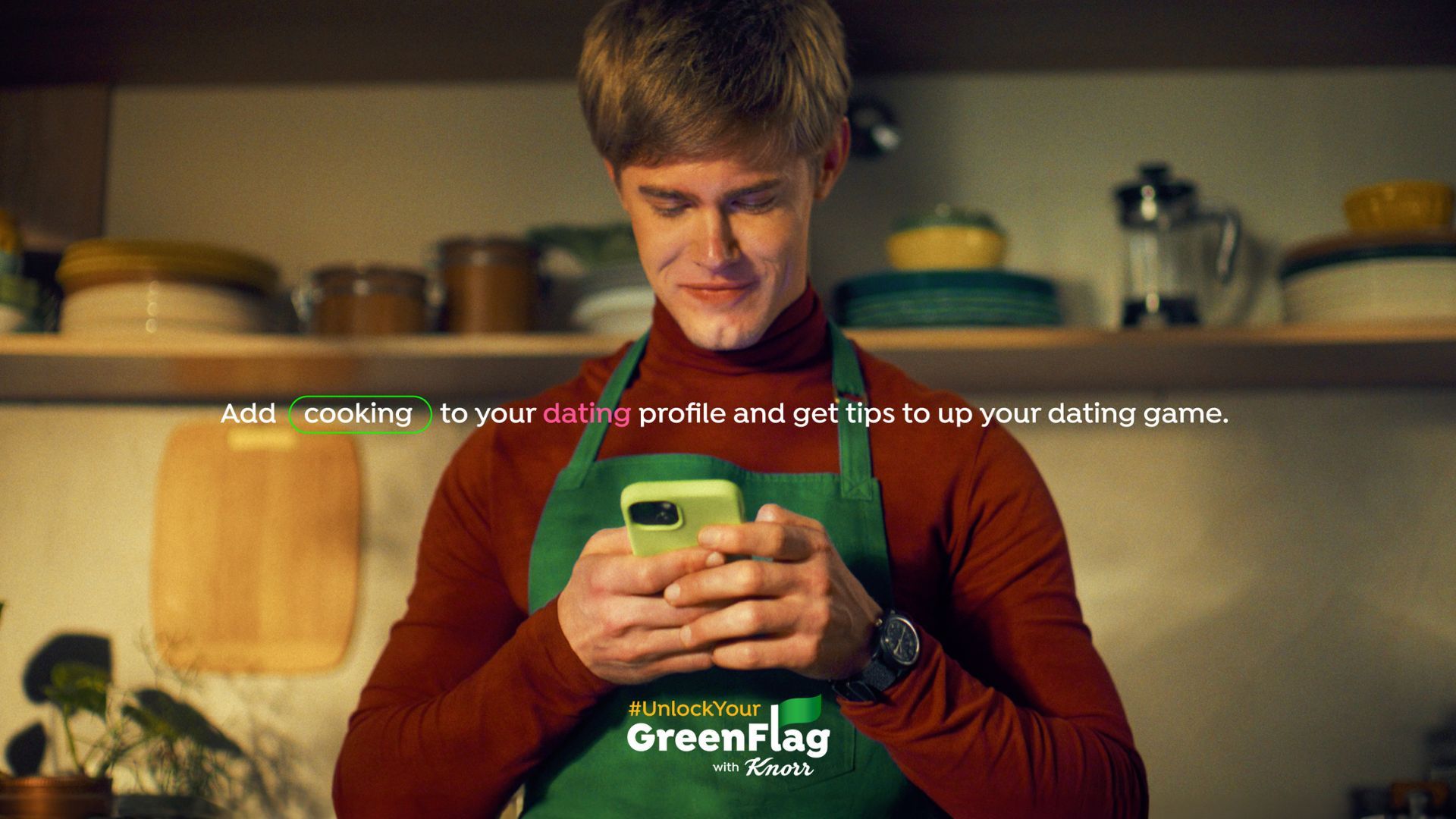 A still from Knorr’s Green Flag social influencer campaign shows a man in a green apron smiling as he looks at his phone .