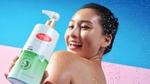 A smiling woman holds Lifebuoy Anti Acne antibacterial body wash -– a white and green bottle with a red Lifebuoy logo.